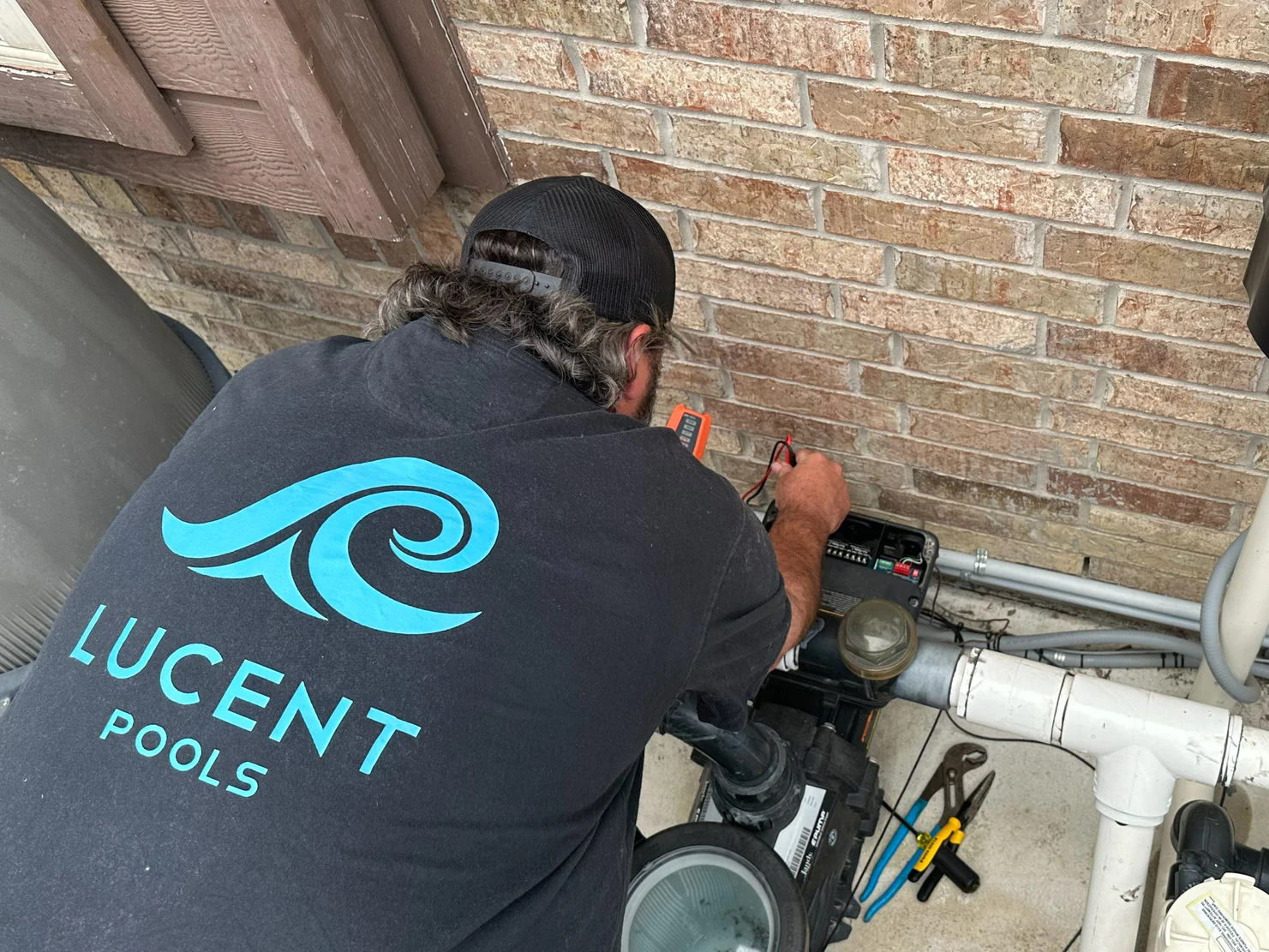 Lucent Pools technician testing a pool pump's electrical controls